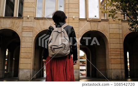 Attractive Woman Walks In City With Backpack, Looking Around 108542720