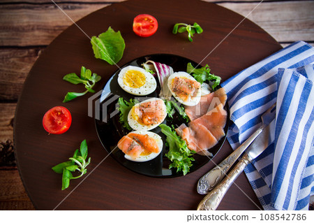 boiled eggs with salted red fish, herbs and seasonings in a plate . 108542786