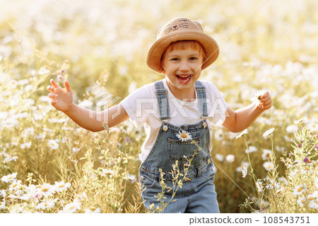 Happy child girl runs through a field of daisies in summer 108543751