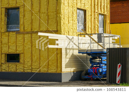Facade siding works with wooden planks after facade spraying with thermal insulation foam 108543811