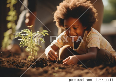 Beautiful little African American boy bending over tiny green sprout in the garden. Adorable child plants a plant in the ground. Fostering a love of nature and concern for environment from childhood. Beautiful little African American boy bending over tiny green sprout in the garden. Adorable child plants a plant in the ground. Fostering a love of nature and concern for environment from childhood. 108544411