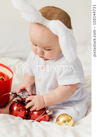Christmas Baby in Santa Hat Child playing with baubles close-up. Present Gift Box over Holiday Lights background and Merry Christmas concept 108544731