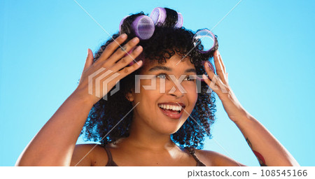Beauty, smile and woman with roller for hair in studio isolated on a blue background. Curlers, hairstyle and African model at hairdresser salon for natural wellness, cosmetics treatment and thinking Beauty, smile and woman with roller for hair in studio isolated on a blue background. Curlers, hairstyle and African model at hairdresser salon for natural wellness, cosmetics treatment and thinking 108545166