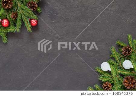 Christmas background with Christmas tree branches and balls decorations in red and white, dark textured background. New Year festive decor. Spruce pine cones. Top view with copy space, flat lay 108545376