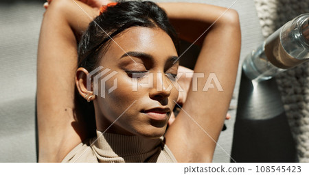 Face, relax and fitness with an indian woman on the floor of her home from above for a workout rest. yoga, exercise and a young sports person resting while training for mental health or wellness 108545423