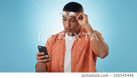 Man, cellphone and shock texting gossip or social media search, internet rumor or surprise communication. Male person, mobile and glasses for secret message, blue studio background as mockup space 108545446
