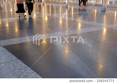A person walking on a path that glitters as it reflects the light. Photographed inside JR Osaka Station 108545773