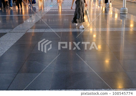 A person walking on a path that glitters as it reflects the light. Photographed inside JR Osaka Station 108545774