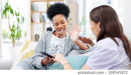 Phone, talking and girl friends on a sofa bonding and networking on social media or mobile app. Happy, discussion and young women scroll on cellphone together in living room of modern apartment. Phone, talking and girl friends on a sofa bonding and networking on social media or mobile app. Happy, discussion and young women scroll on cellphone together in living room of modern apartment. 108545872