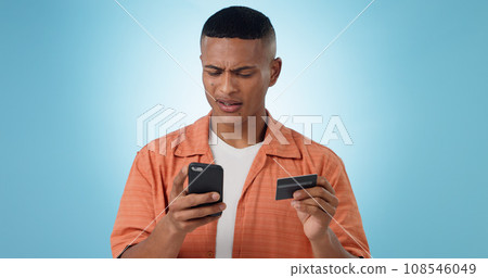 Man, credit card and phone in studio, frustrated face or confused with thinking, fintech and blue background. Person, smartphone and online shopping with glitch, payment decline and fail with banking 108546049