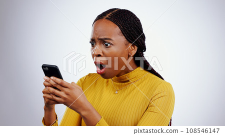 Woman, reading phone and shocked for news, social media and online error or mistake on a white background. African person confused, surprise and stress on mobile for scam or notification in studio Woman, reading phone and shocked for news, social media and online error or mistake on a white background. African person confused, surprise and stress on mobile for scam or notification in studio 108546147