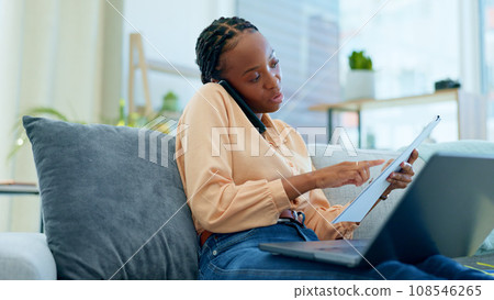 Woman, phone call and laptop with documents for remote work from home, reading and talk on lounge sofa. African entrepreneur, freelancer person and check paperwork with smartphone, computer and couch 108546265