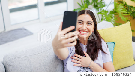 Woman, video call and sofa with smile, home and happy on web blog, internet and relax in living room. Influencer girl, excited and live streaming for memory, contact and social network app on couch Woman, video call and sofa with smile, home and happy on web blog, internet and relax in living room. Influencer girl, excited and live streaming for memory, contact and social network app on couch 108546324