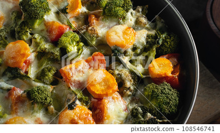 Gratin with broccoli, carrots and cheese baked in the oven on a dark wooden table, close up Gratin with broccoli, carrots and cheese baked in the oven on a dark wooden table, close up 108546741