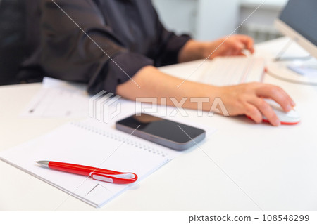 A notebook with a pen and an office worker or student in the background 108548299