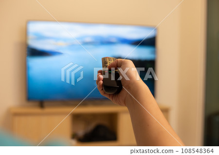 Hand holding TV remote control Hand holding TV remote control 108548364