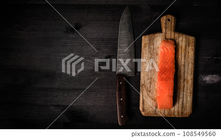 fillet of raw salmon red fish on a cutting board with a big kitchen knife, top view with a copy space fillet of raw salmon red fish on a cutting board with a big kitchen knife, top view with a copy space 108549560