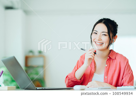一名年輕女子在客廳線上學習。 一名年輕女子在客廳線上學習。 108549934