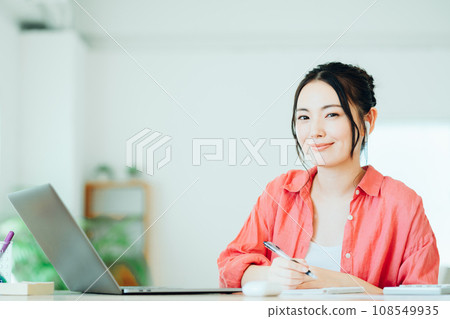 A young woman studies online in her living room. A young woman studies online in her living room. 108549935