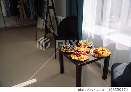 Cold appetizers and sliced fruits in plates on a small table Cold appetizers and sliced fruits in plates on a small table 108550574