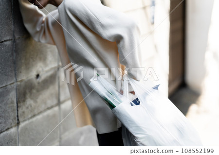 A woman holding her waist on her way home from shopping A woman holding her waist on her way home from shopping 108552199