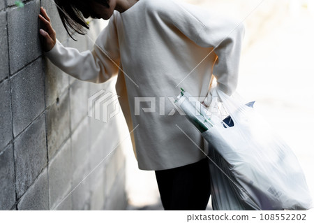 A woman holding her waist on her way home from shopping 108552202