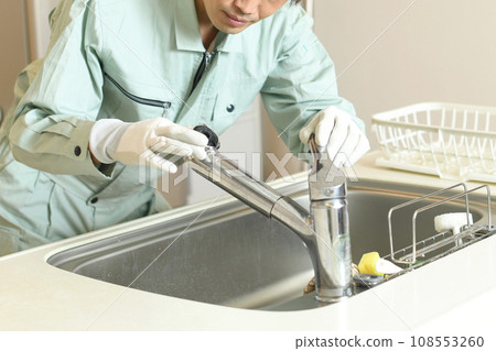 一名工人正在檢查延伸到廚房的沖洗水龍頭 一名工人正在檢查延伸到廚房的沖洗水龍頭 108553260