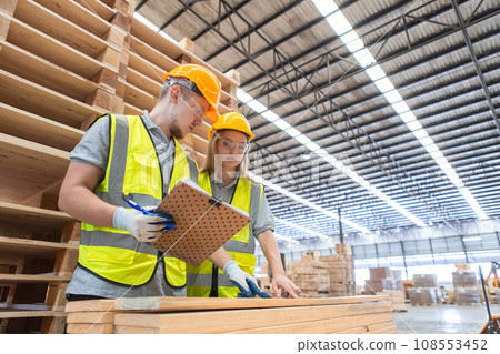 Team engineer carpenter wearing safety uniform and hard hat working holding clipboard Team engineer carpenter wearing safety uniform and hard hat working holding clipboard 108553452