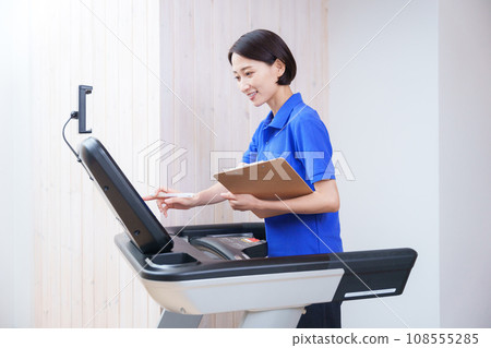 Female staff checking training machines at a sports gym 108555285