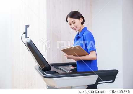 Female staff checking training machines at a sports gym Female staff checking training machines at a sports gym 108555286