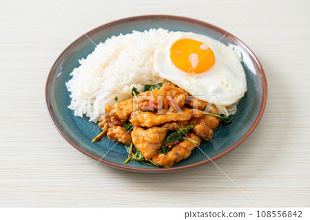 stir-fried fried fish with basil and fried egg topped on rice 108556842