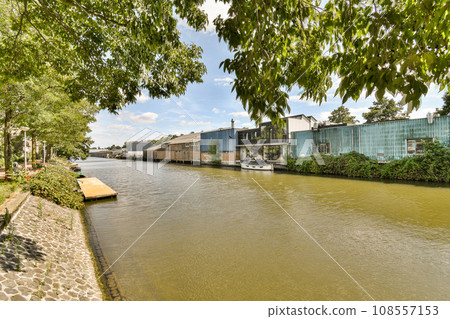 a river with buildings and trees in the fore, taken from a boat on the water's edge as it passes by 108557153