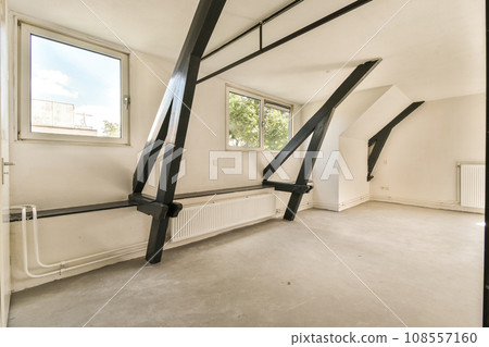 an empty room with white walls and black metal pipes on the wall, there is a window in the corner 108557160