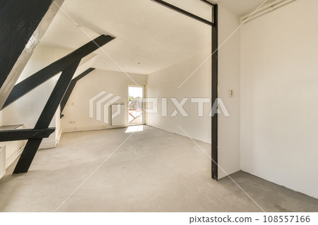 an empty room with white walls and black metal beams on the wall, there is a window in the corner 108557166
