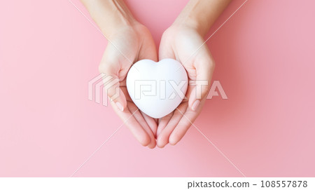 Female hands gently holding the heart. Pink background. 108557878