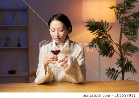 A woman relaxing while drinking red wine 108557911