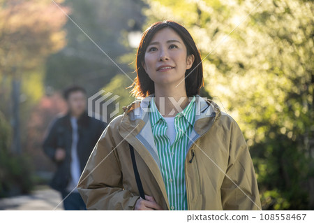一個女人在秋天的公園散步，一個男人跟著她 108558467