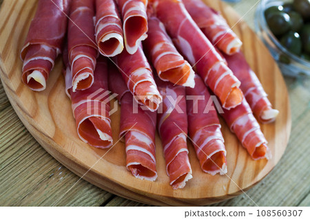 Spanish tapas - rolls of jamon serrano served on wooden board 108560307