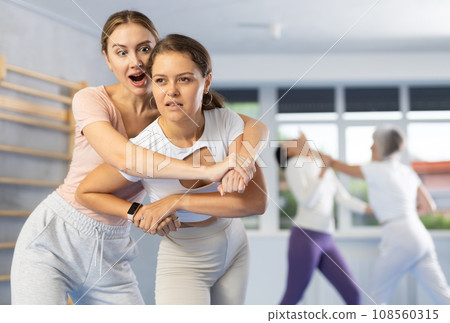 Woman escaping from back grip and delivering elbow strike to midsection in self-defense training Woman escaping from back grip and delivering elbow strike to midsection in self-defense training 108560315
