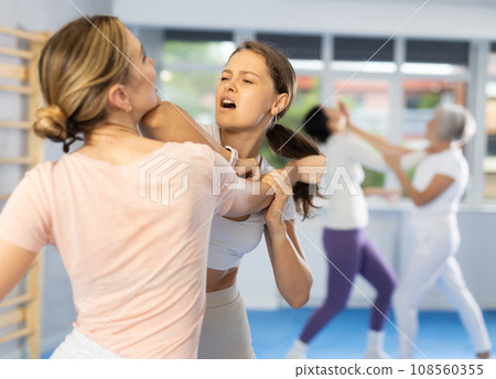 Young woman practicing arm lock with elbow strike to chin in mock bout 108560355