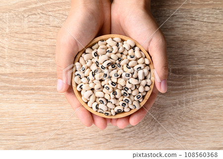 Black eye peas or cowpeas in bowl holding by hand on wooden background 108560368