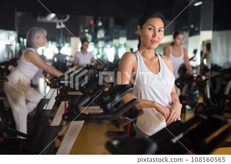 Asian woman with fitness bike in gym Asian woman with fitness bike in gym 108560565