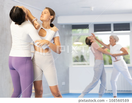 Woman and girl in gym perform basic elements of krav maga self-defense system. 108560589