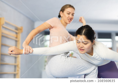 Woman and girl in gym perform basic elements of krav maga self-defense system. Woman and girl in gym perform basic elements of krav maga self-defense system. 108560635