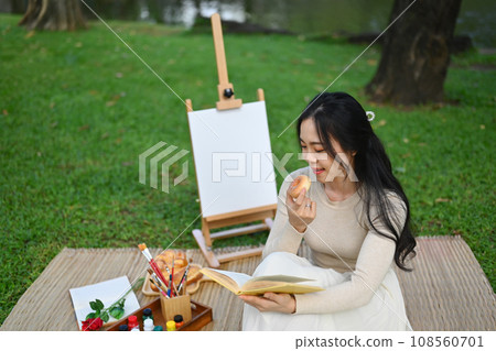 Relaxed young woman reading interesting book and enjoying free time at green park 108560701