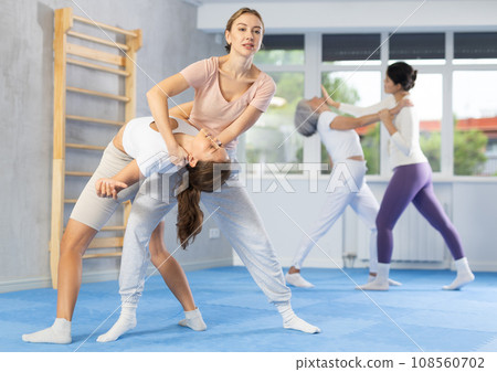 Young woman applying inverted headlock during mock bout in self-defense training 108560702