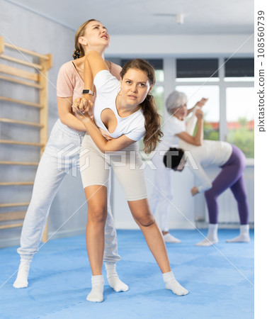Young girl trying to escape rear grab and striking chin with elbow during self defense course Young girl trying to escape rear grab and striking chin with elbow during self defense course 108560739