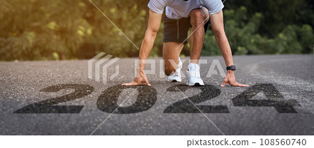 Man athlete in starting position on road with numbers 2024 symbolizes start of the new year Man athlete in starting position on road with numbers 2024 symbolizes start of the new year 108560740