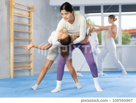 Woman and girl in gym perform basic elements of krav maga self-defense system. Woman and girl in gym perform basic elements of krav maga self-defense system. 108560867