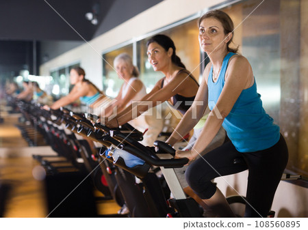 Elderly woman warming up on bike at gym 108560895